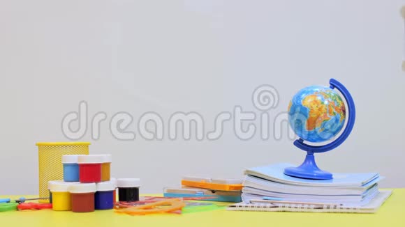 桌子上有写字的材料一个孩子手把彩色铅笔放进玻璃杯里视频的预览图