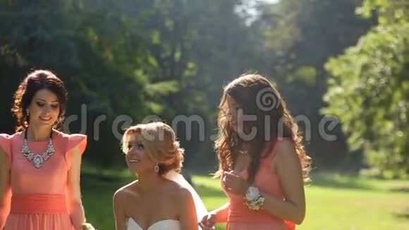 美丽的金发新娘正在和她的两个穿着橙色连衣裙的迷人玩她正在举办婚礼视频的预览图