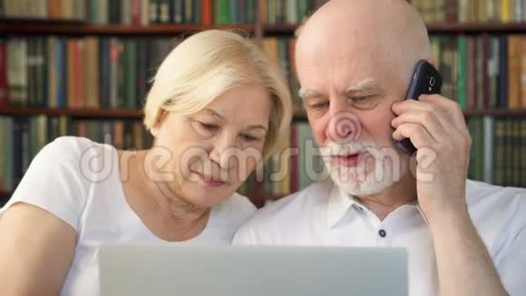 家里的老夫妇带着笔记本电脑退休养老金领取者家庭使用电话讨论屏幕上的sm视频的预览图