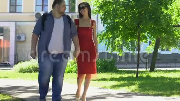 美丽的苗条女人穿着红色连衣裙和肥胖的男朋友牵手做梦吧视频的预览图