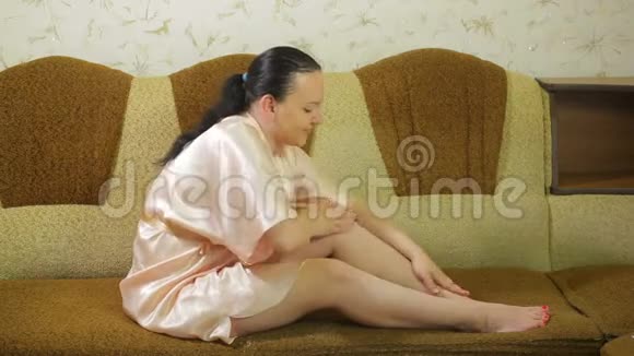 沙发上的一位年轻女士脱毛后将滑石粉涂在腿上视频的预览图