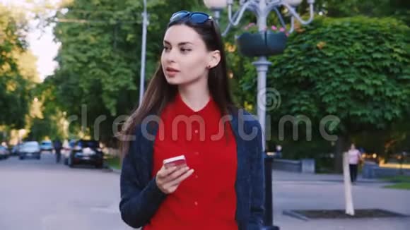 迷人的女人走在街上享受着智能手机视频的预览图