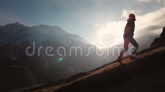 在美丽的日落中一个人在山的边缘行走作为一个剪影的史诗镜头的鸟瞰剪影视频的预览图