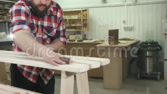 木匠穿着一件有胡须的衬衫在车间里工作给一个木凳加热视频的预览图
