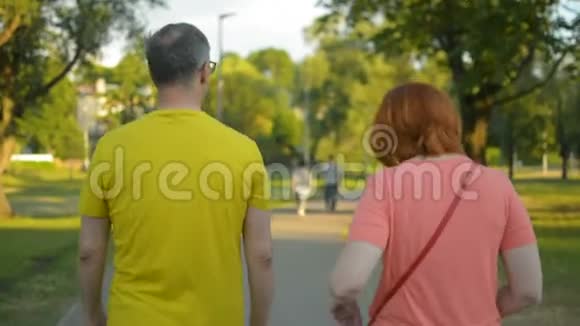 新婚夫妇穿着五颜六色的夏装傍晚时分在公园散步视频的预览图