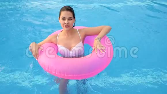 在泳池边的粉色充气戒指上女性的积极姿态视频的预览图