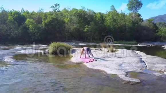 在河石的瑜伽姿势中腿上的女孩平衡视频的预览图