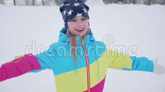 快乐的女孩躺在雪地上展示天使一个穿外套的漂亮女孩躺在雪地上张开双臂视频的预览图