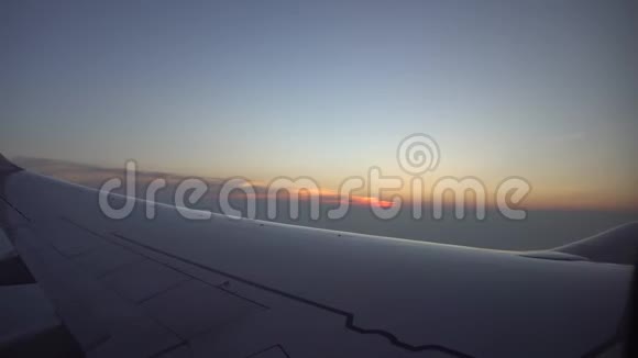 从飞机窗口日落观橙色的太阳飞机的翅膀黑暗的天空和云彩视频的预览图