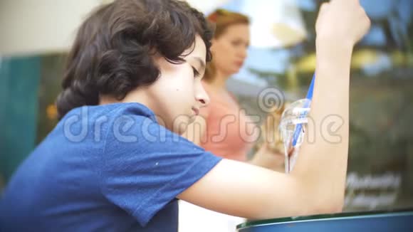 悲伤的少年坐在咖啡馆的桌子旁手里拿着一块巧克力奶昔4k慢动作视频的预览图