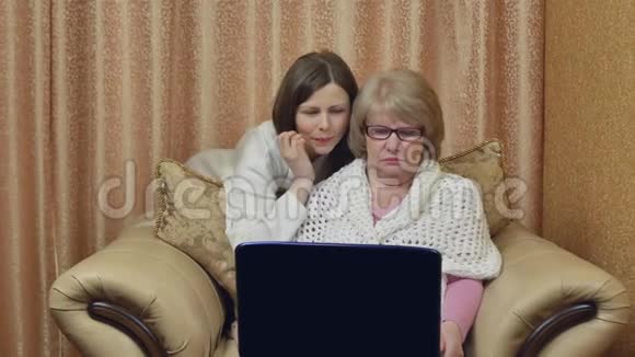开朗的母女享受视频通话看着笔记本电脑屏幕微笑着坐在家里的椅子上视频的预览图
