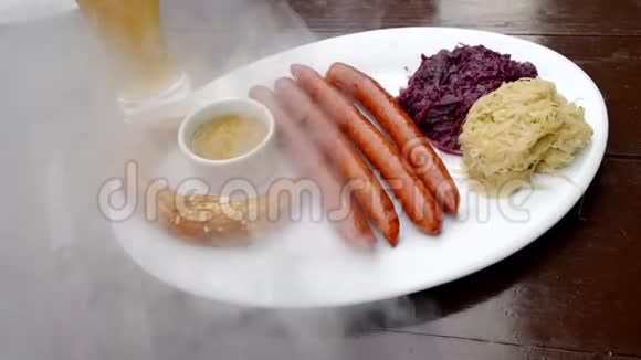一个盘子里放着德国香肠和卷心菜旁边放着一杯啤酒客户把盘子放在他的盘子里关门视频的预览图