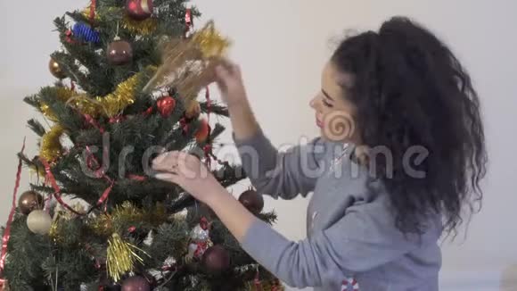 美丽的女人把金色的星星放在圣诞树上视频的预览图