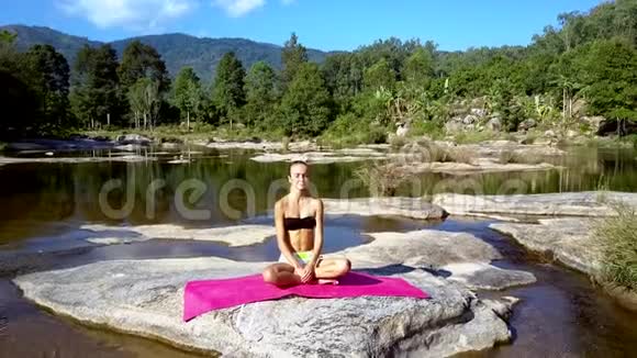 女孩在河边和远山间休息做瑜伽视频的预览图