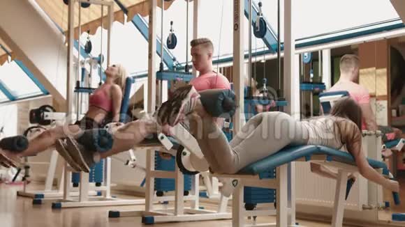 三个在健身房运动的朋友肌肉发达的男人和骨瘦如柴的女人在一起工作4k视频的预览图