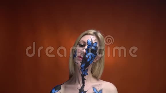 一个金发碧眼的金发女郎脸上画着一幅蝴蝶画审视着她周围的领地视频的预览图