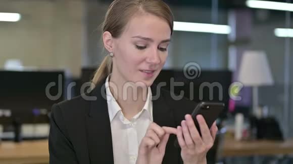 年轻女商人庆祝智能手机成功的画像视频的预览图