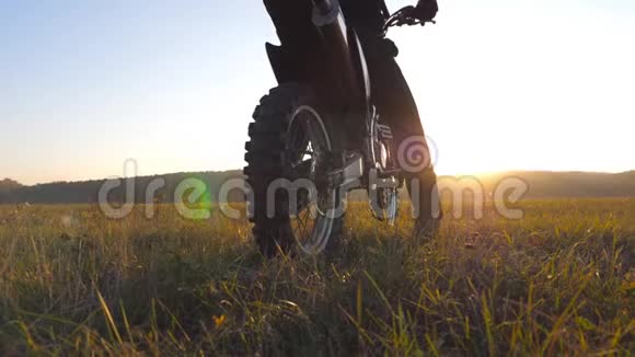 不可辨认的摩托车骑手坐在他的摩托车在大田野上美丽的日落背景运动员视频的预览图