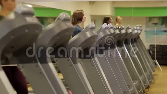 女孩在健身房的跑步机上跑步它反映在镜子里视频的预览图
