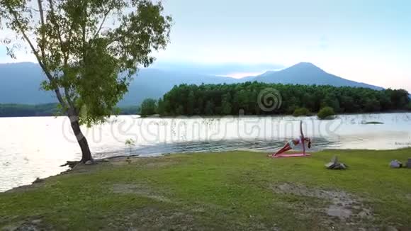 粉色垫子上的女孩在漂亮的湖上摆姿势视频的预览图