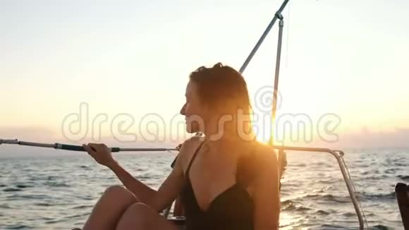 穿着泳衣的快乐微笑的女人坐在游艇上欣赏日落美景视频的预览图