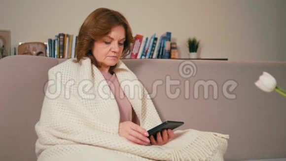 成年女士正在用平板电脑在舒适的房间里阅读传统书籍视频的预览图
