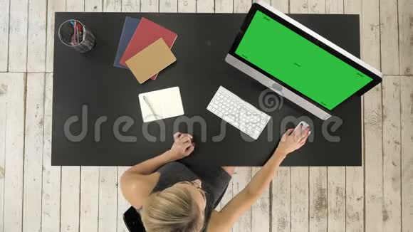 年轻女子在她的办公桌上用电脑工作绿色屏幕模拟显示视频的预览图