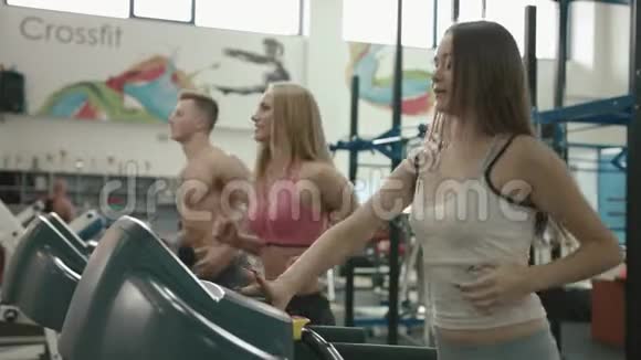 健康的生活方式理念三个运动的朋友正在现代健身房的跑步机上闲逛4k视频的预览图