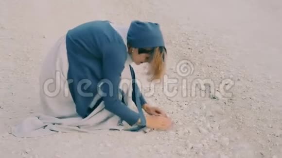 快乐的女孩穿着奢侈的衣服光着脚在沙地路上扔石头玩得很开心视频的预览图