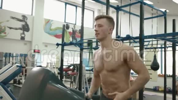 性感的肌肉男赤裸的躯干在现代健身房的跑步机上热身4K录像视频的预览图