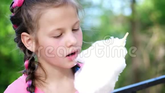 肖像画八岁的漂亮女孩金发有雀斑还有多种颜色的辫子吃白色棉花棉花视频的预览图