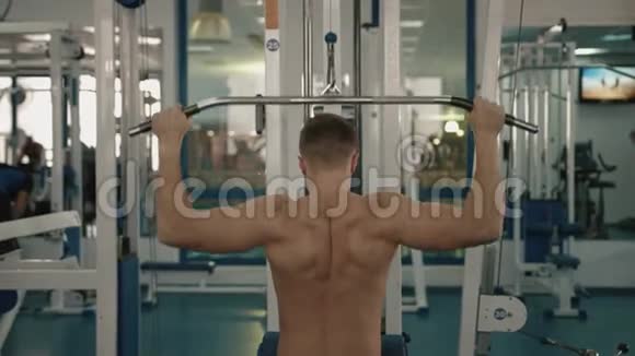 一个身材赤裸的无名男子正在健身站训练他的背部和抽铁后景4k视频的预览图