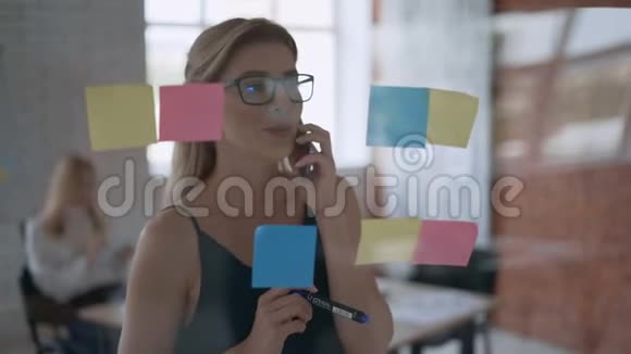 一个成功的女孩中弹严肃的商业女性在电话上交谈和在贴纸上做笔记的肖像视频的预览图