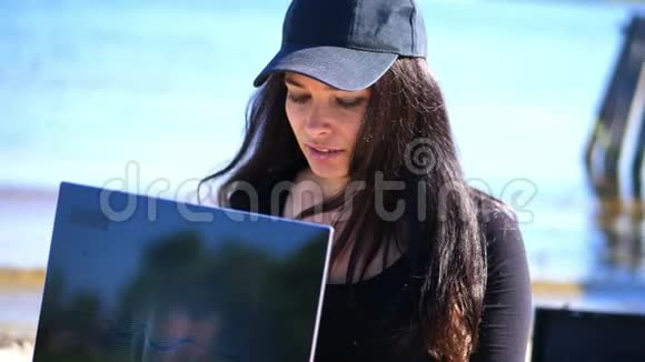 夏天海边日出戴着黑帽子的美女布莱瑟在用笔记本电脑视频的预览图