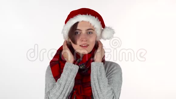 戴着圣诞帽和冬巾的快乐女人对着镜头微笑视频的预览图