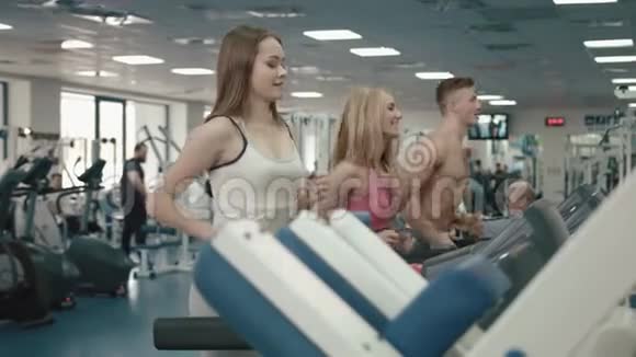 健身房的健康和运动理念三个健康迷人的女运动员和运动员在特里德米尔跑步4k视频的预览图