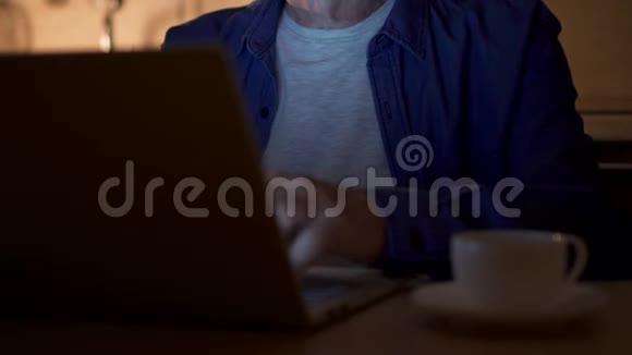 老人在使用笔记本电脑时喝杯咖啡在家庭办公室工作的自由职业者视频的预览图