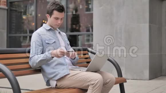 坐在长凳上的年轻人在网上购物视频的预览图