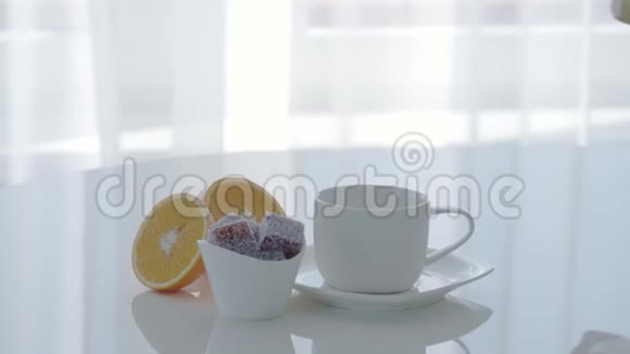 在一张白色的桌子上特写一杯茶和果酱女人喝茶视频的预览图