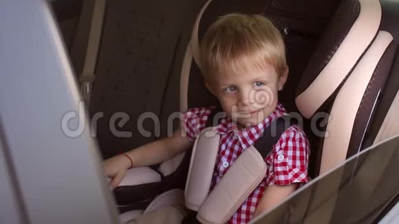 小快乐的男孩坐在一辆小汽车的座位上竖起大拇指视频的预览图