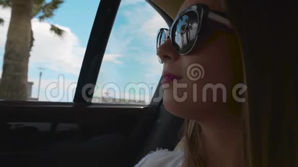戴太阳镜的漂亮女人透过车窗欣赏海滩美景出租车服务视频的预览图
