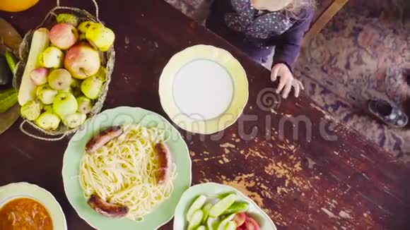 小女孩坐在桌子旁靠近空盘子等待食物妈妈提供午餐视频的预览图