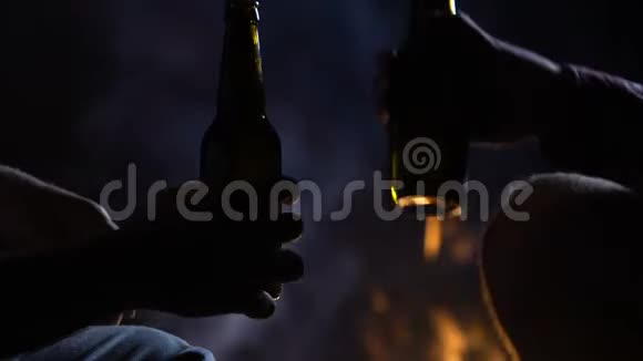 两个男性朋友喝瓶装啤酒庆祝凉爽的营地假期特写视频的预览图