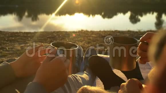 一对夫妇坐在湖边碰着茶杯享受美丽的日落放松一下视频的预览图