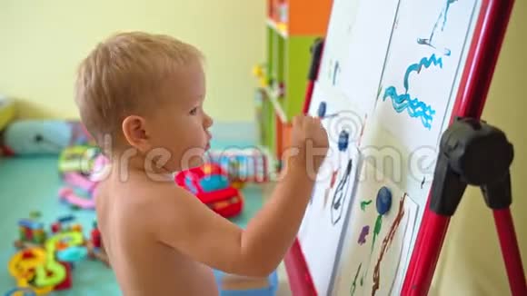 可爱的男孩在画架上画画视频的预览图
