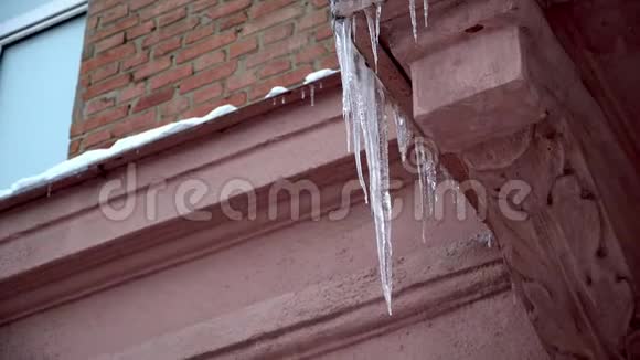 冬天的冰柱在春天的阳光下在屋顶上融化从它们的顶端滴落下来的危险视频的预览图