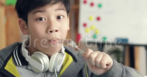 一幅年轻的亚洲男孩吃着看着一个微笑着的相机的肖像多莉向右向左移动视频的预览图