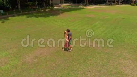 一对年轻夫妇在热带公园接吻的空中镜头视频的预览图