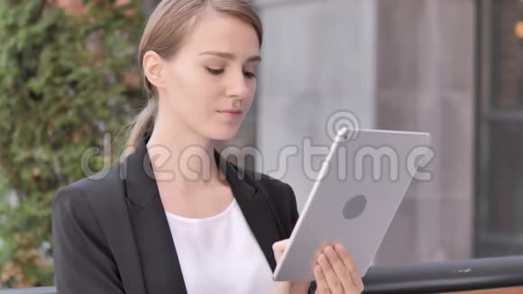年轻女商人坐在户外和使用餐桌视频的预览图