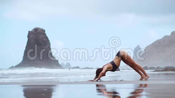 一个穿着泳衣的年轻苗条金发女孩戴着黑色大耳机听音乐在热带海滩上跳舞视频的预览图